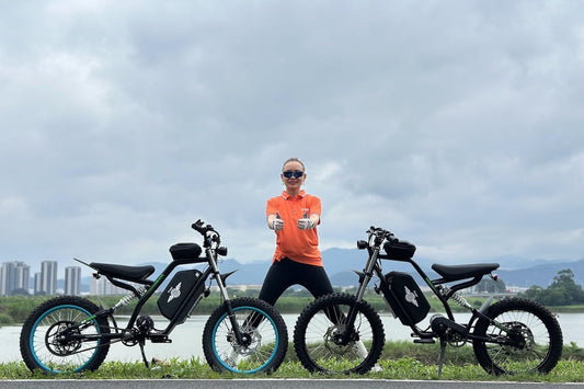 A woman in an orange t-shirt standing between the two Freego Nova 3 with the river in the background