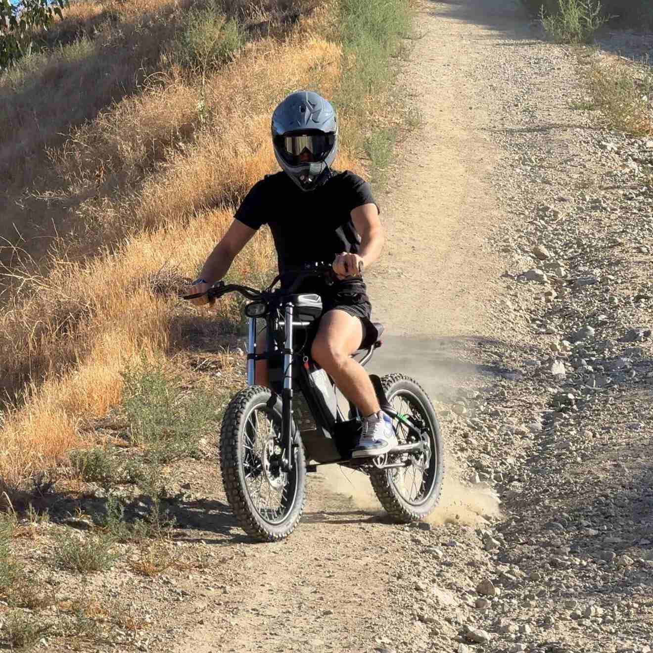 Person riding a dirt bike on a gravel path in a natural setting