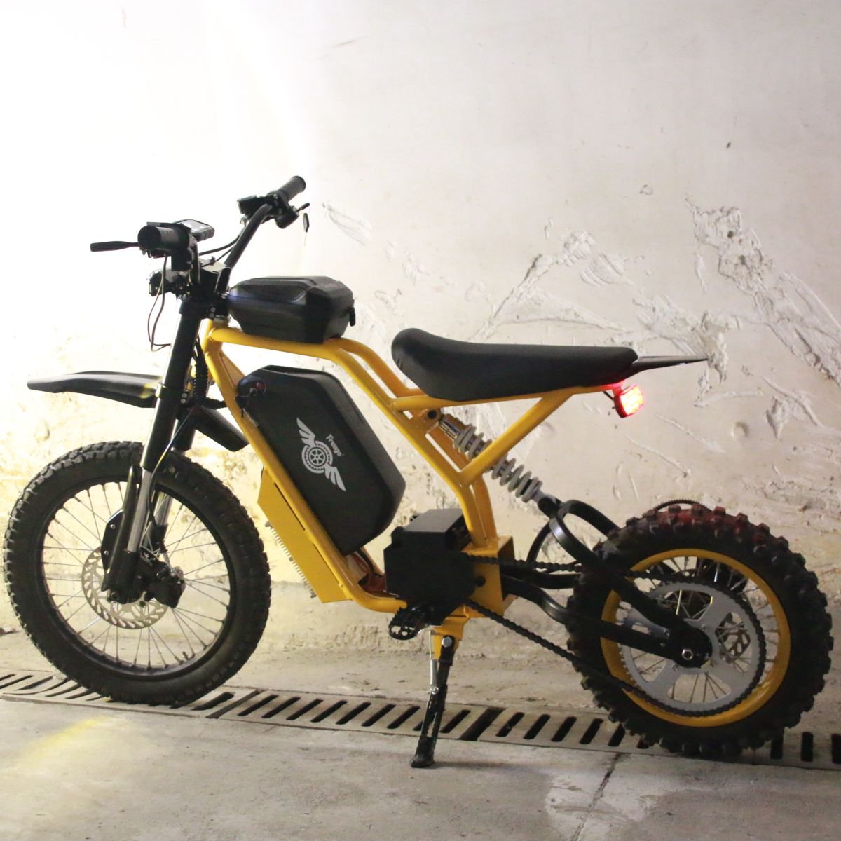 Yellow electric bike with black seat and tires against a white wall.