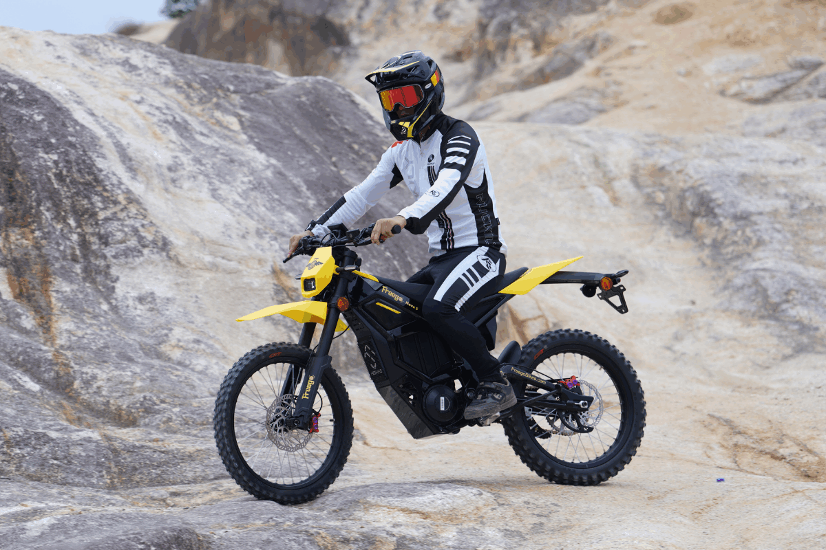 Person riding a yellow electric bike on rocky terrain