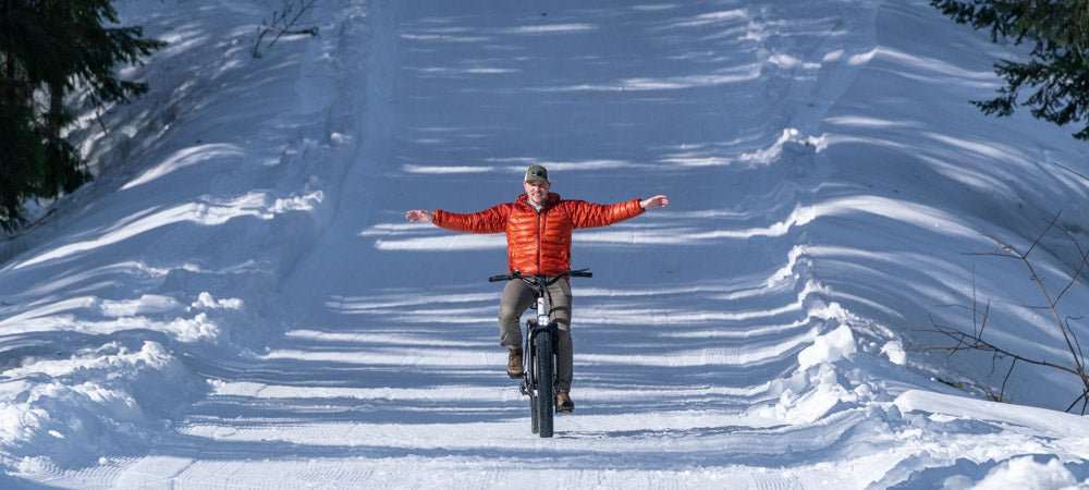 Man riding e-bike on snowy trail wearing orange jacket winter riding safety tips