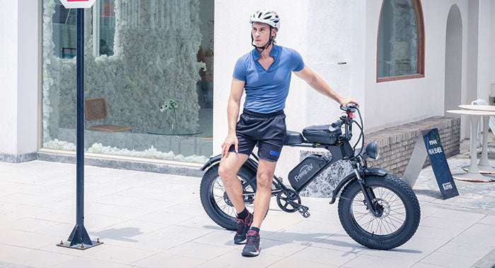 A sporty man leaning on the black Freego DK200 at the corner of the street