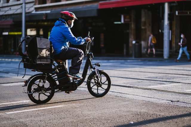Person wearing helmet riding an electric bike in a city street for eco-friendly commuting