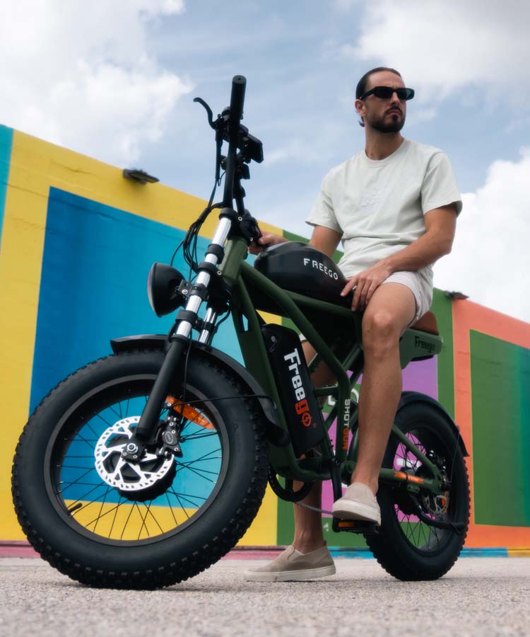 A man sitting on a black Freego F3 Pro against the colorful wall