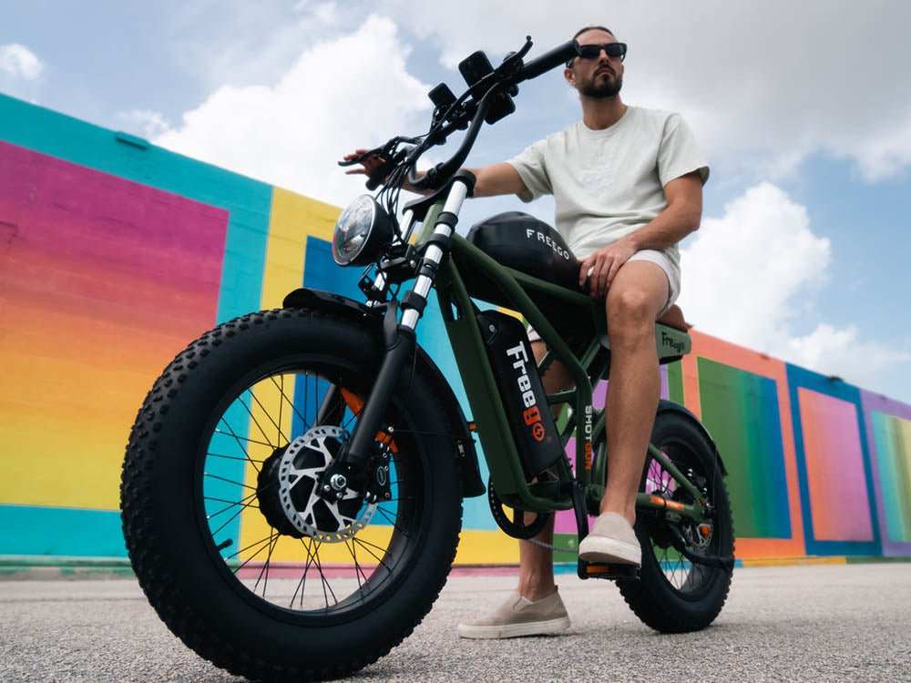 A man sitting on a Freego Flash F3 Pro against the colorful wall happy for learning about eBike classes explained in our community