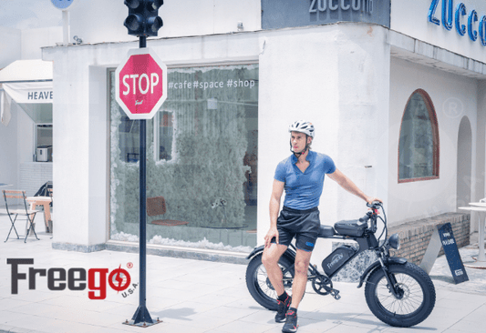 Man wearing helmet sitting on black FreeGo DK200 electric bike near stop sign outside a cafe