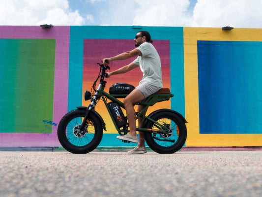 Man riding green electric bike Freego against colorful mural wall for back-to-school commuting guidance