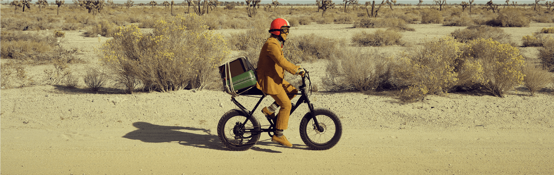 Man riding electric cargo bike on desert trail with cargo box on back
