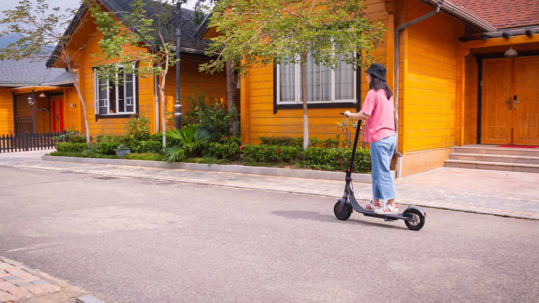 woman riding electric kick scooter on residential street near wooden houses