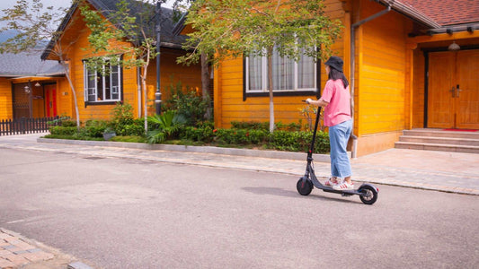 woman riding electric kick scooter on residential street near wooden houses