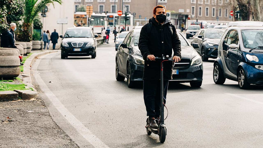 Man riding electric scooter on city street wearing mask to get a full experience with scooter steps