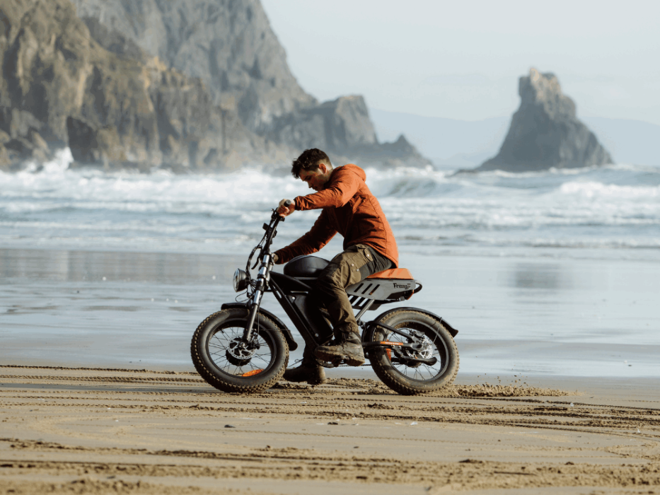 A young man riding Freego F3 Pro Max on the beach, with the strong waves in the background
