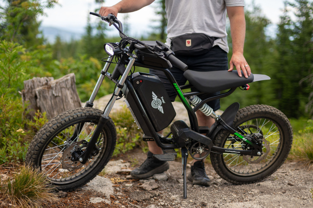 A man in the forest standing behind a black Freego Nova 3 dirt electric bicycle with fluorescent green details