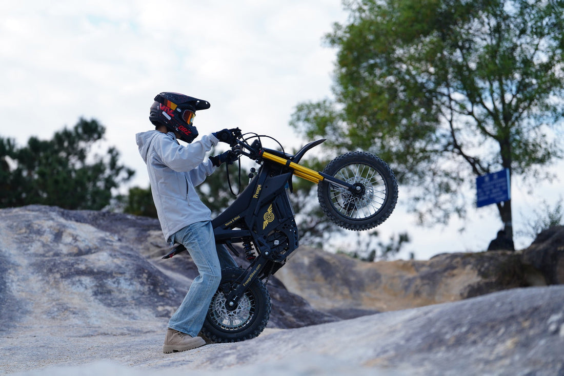 Rider performing a controlled wheelie on the Nova 5 Mini on a rocky mountain trail, wearing a helmet for off-road safety