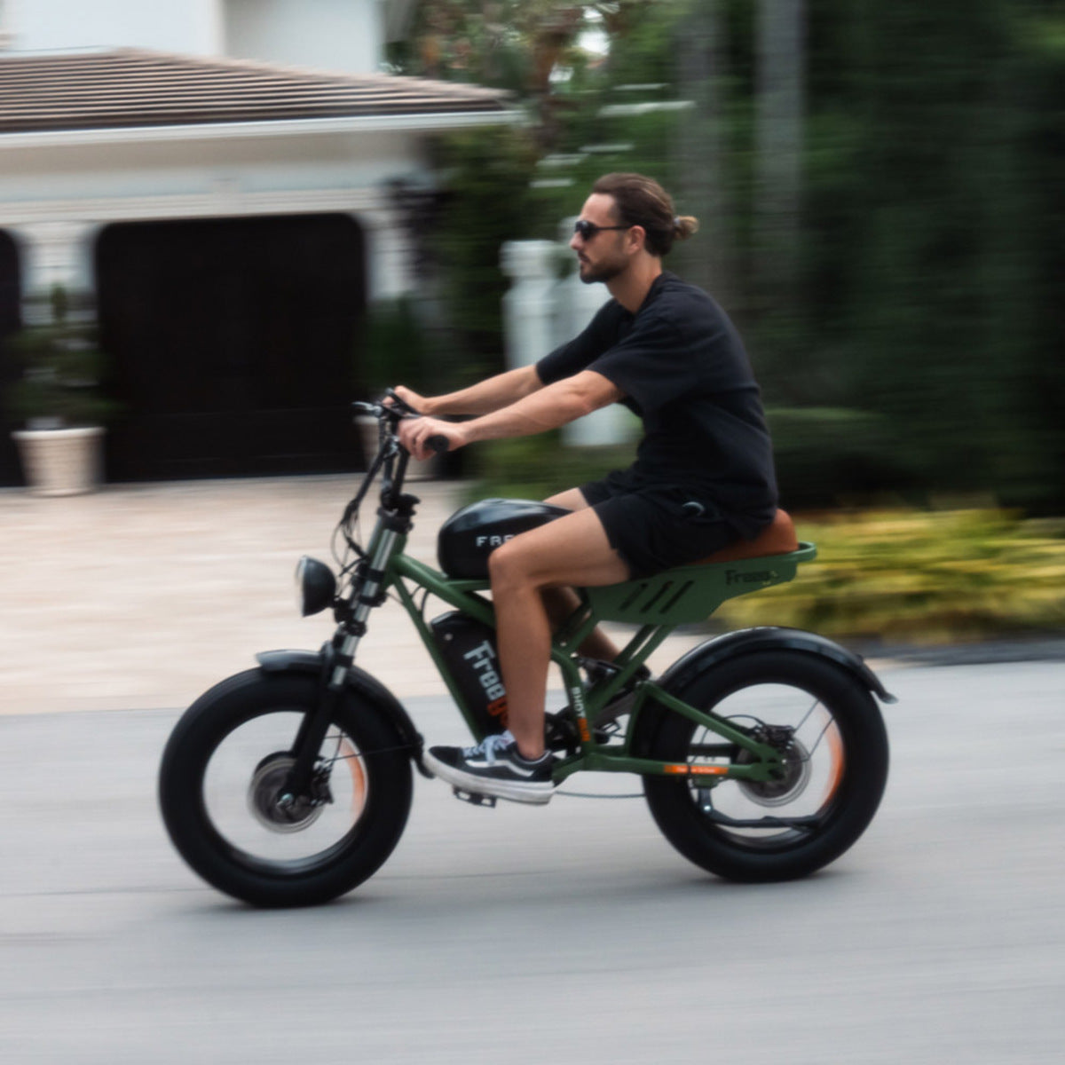 Man riding a green Freego F3 Pro e-bike on a road with blurred background