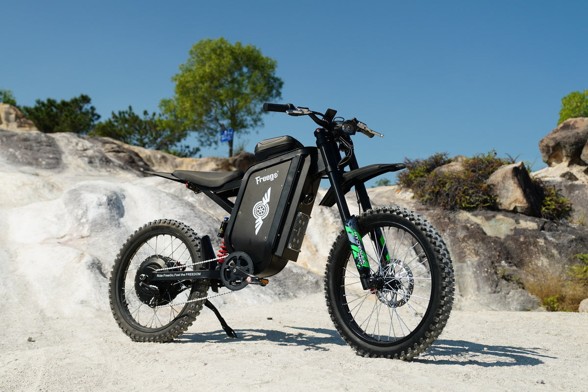Black Freego X3 electric bike on a rocky outdoor landscape with trees in the background