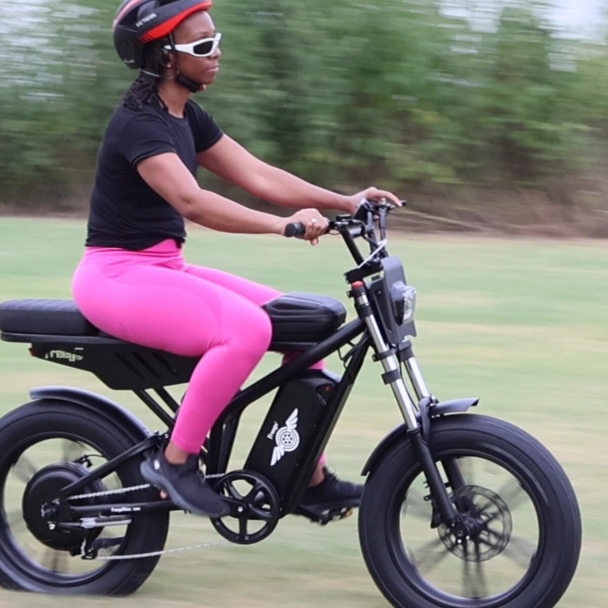 Person riding a black electric bike on a grassy area