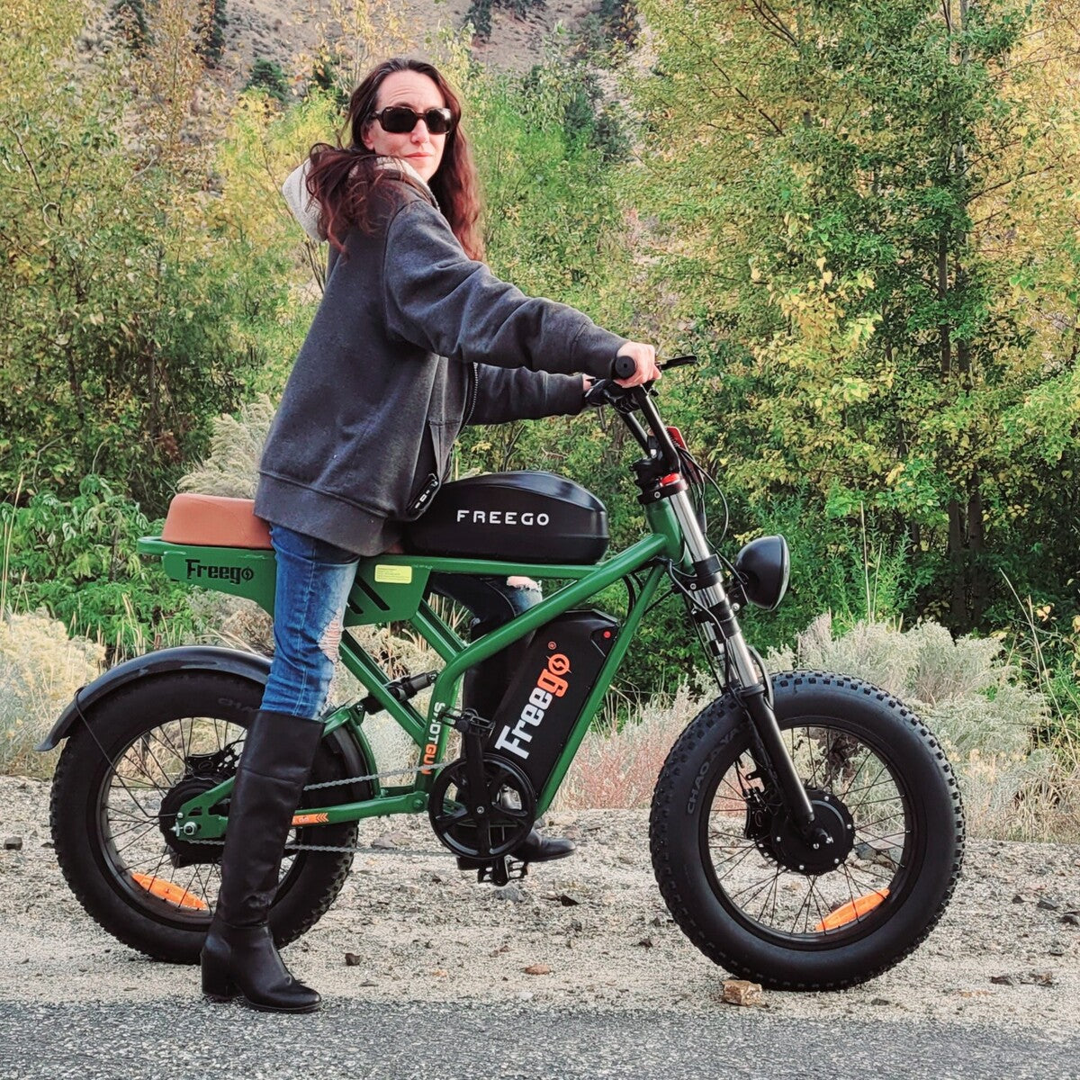 Woman standing next to a green Freego F3 Pro in a forested area