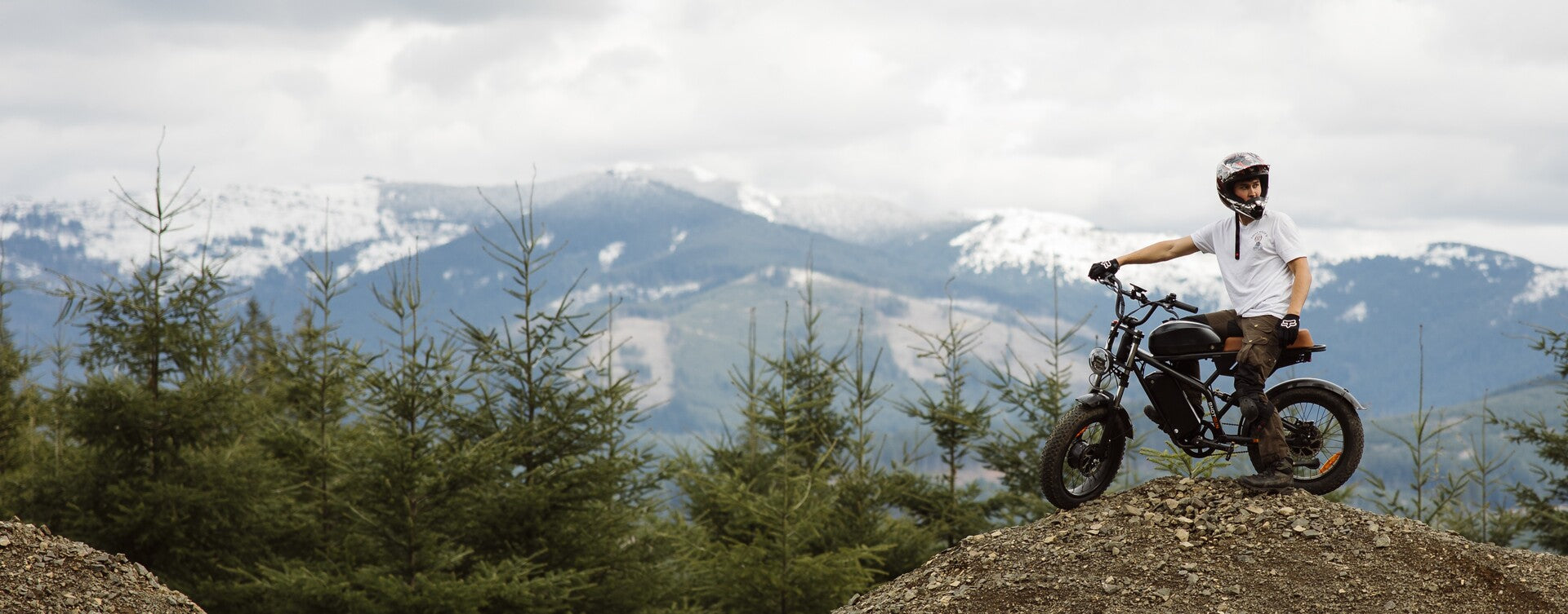 Person riding a Freego F3 Pro on a rocky outcrop with mountains in the background