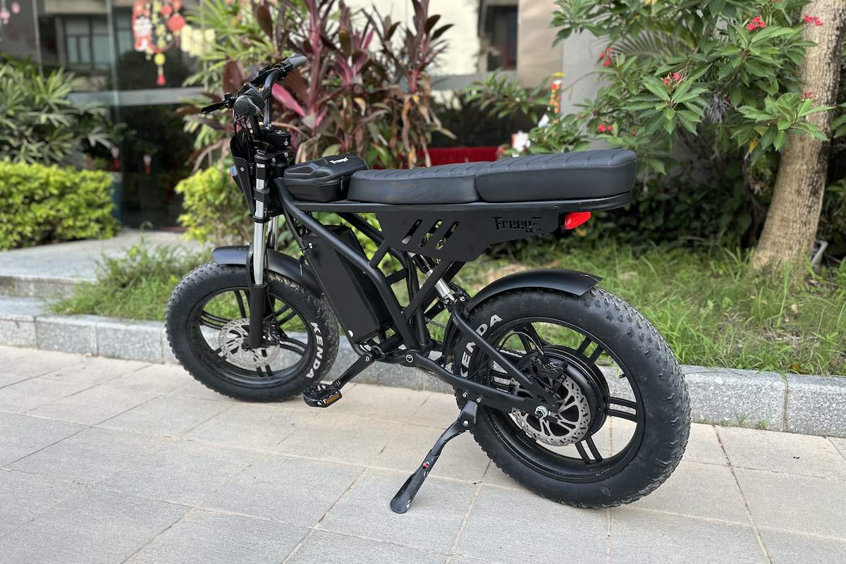 Freego F2 Pro Max electric bike with long seat and Kenda tires parked near greenery.