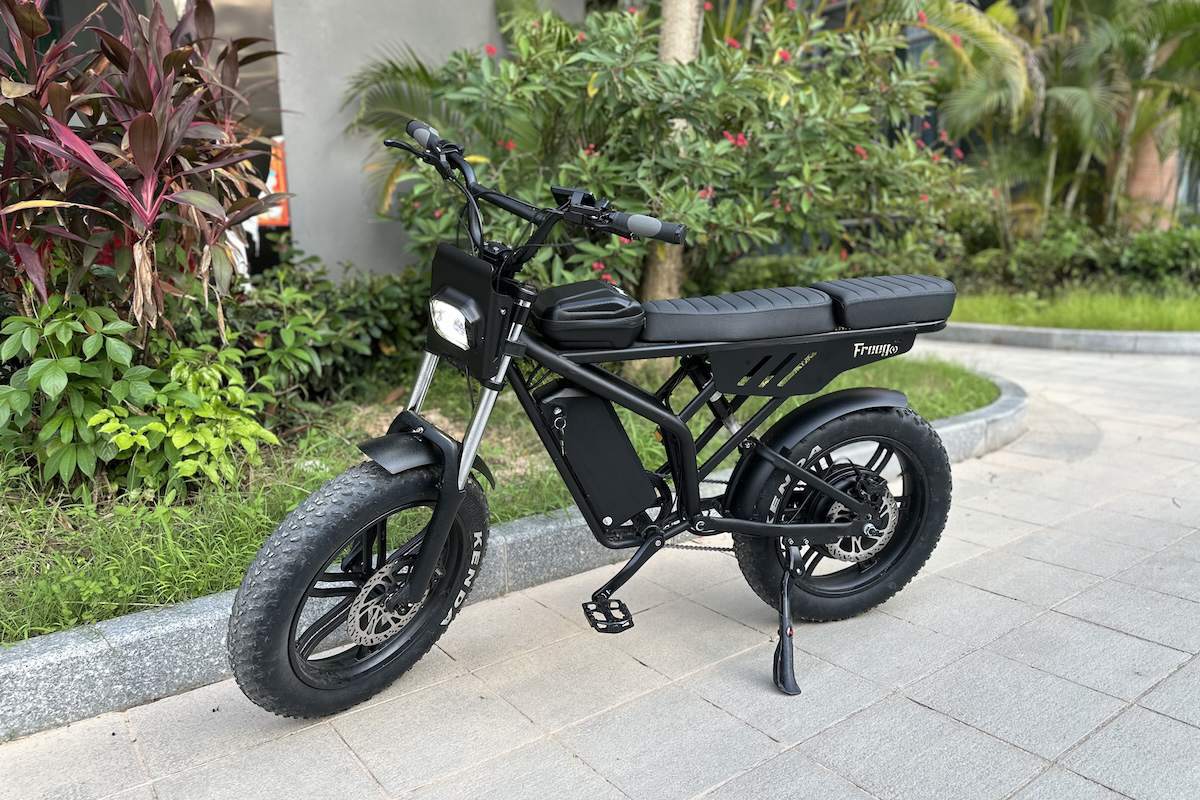 Freego F2 Pro Max electric bike with headlight and fat tires parked on a tiled path near plants.