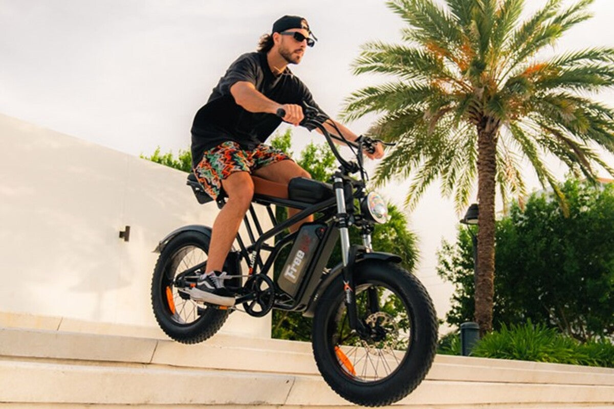 Man riding an electric bike outdoors with palm trees in the background