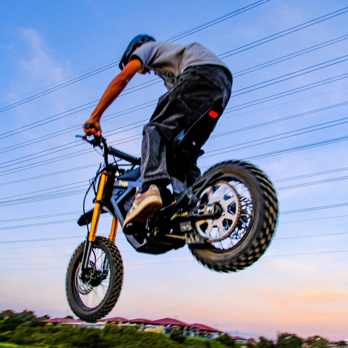 Rear view of a rider jumping the Freego Nova 5 Mini during an off-road ride on a dirt trail.