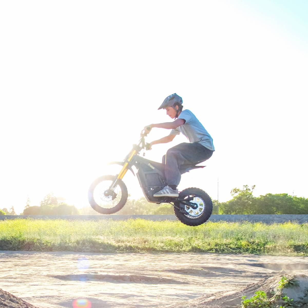 Rider performing a small jump on the Freego Nova 5Mini while riding on a dirt trail in an off-road environment.