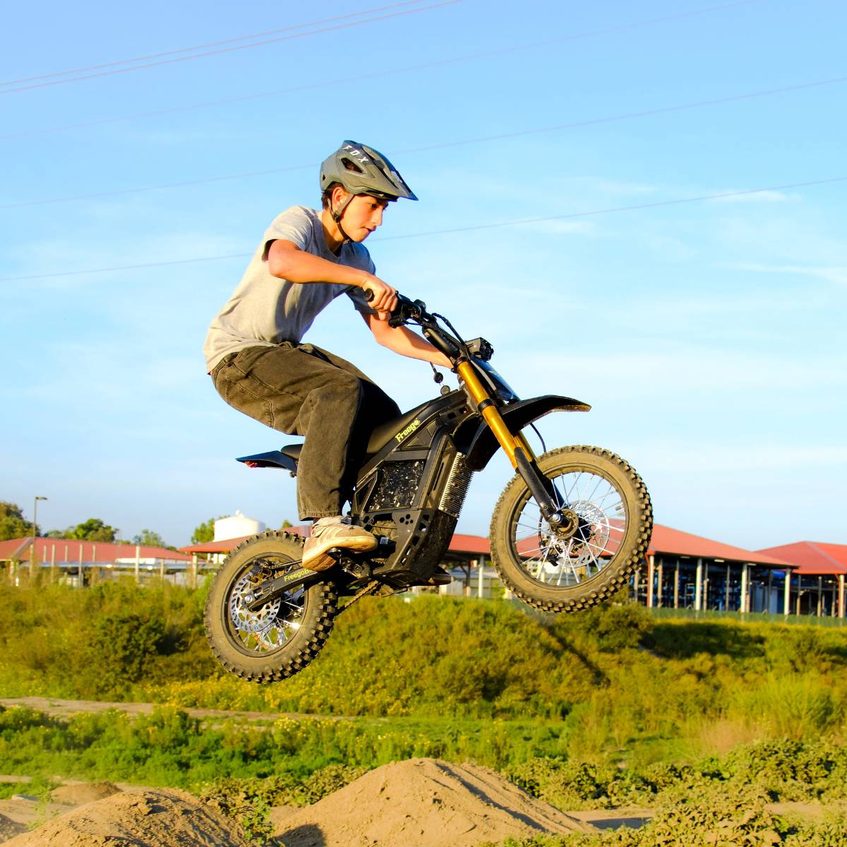 Rider jumping the Freego Nova 5 Mini during an off-road ride on a dirt trail.