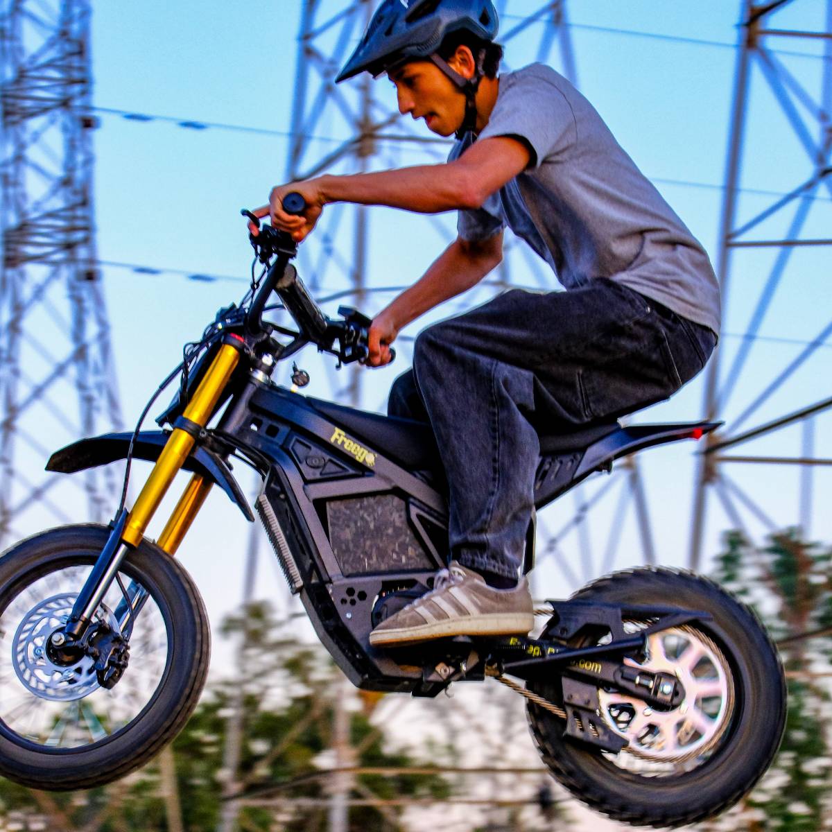 Rider in mid air riding the Freego Nova 5 Mini on an off-road trail.