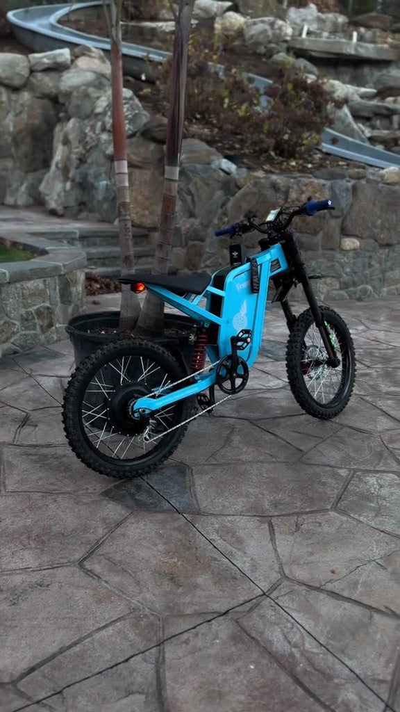 Blue Freego X2 Pro electric bike on a stone patio with stone wall background
