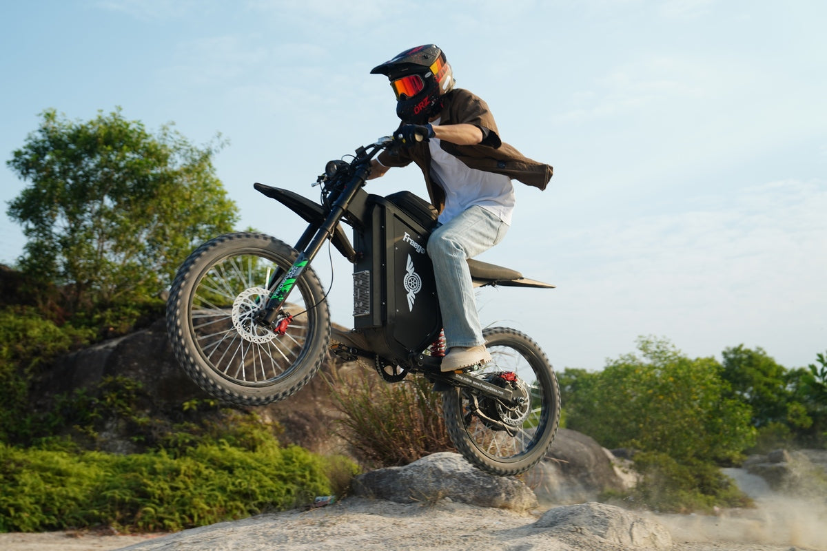 Freego X3 ebike - Person riding a black electric bike on a rocky trail with trees in the background