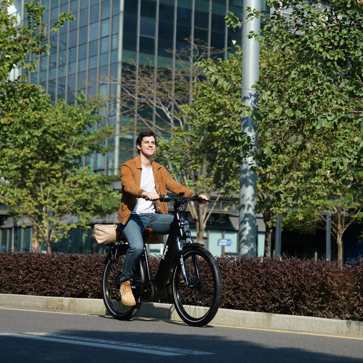Man riding a Freego City Flow A1 Electric Bike on a city street with modern buildings and trees in the background