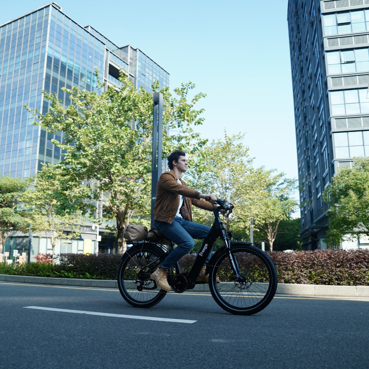 Man riding an Freego City Flow A1 Electric Bike on a city street with modern buildings and greenery.