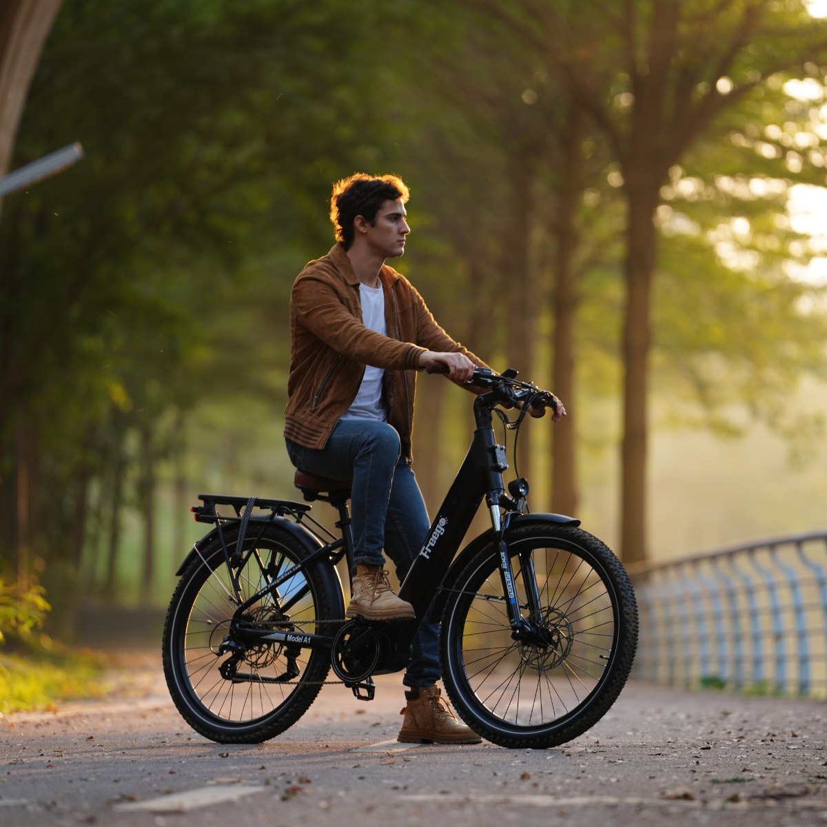Man riding an Freego City Flow A1 Electric Bike on a path with trees in the background
