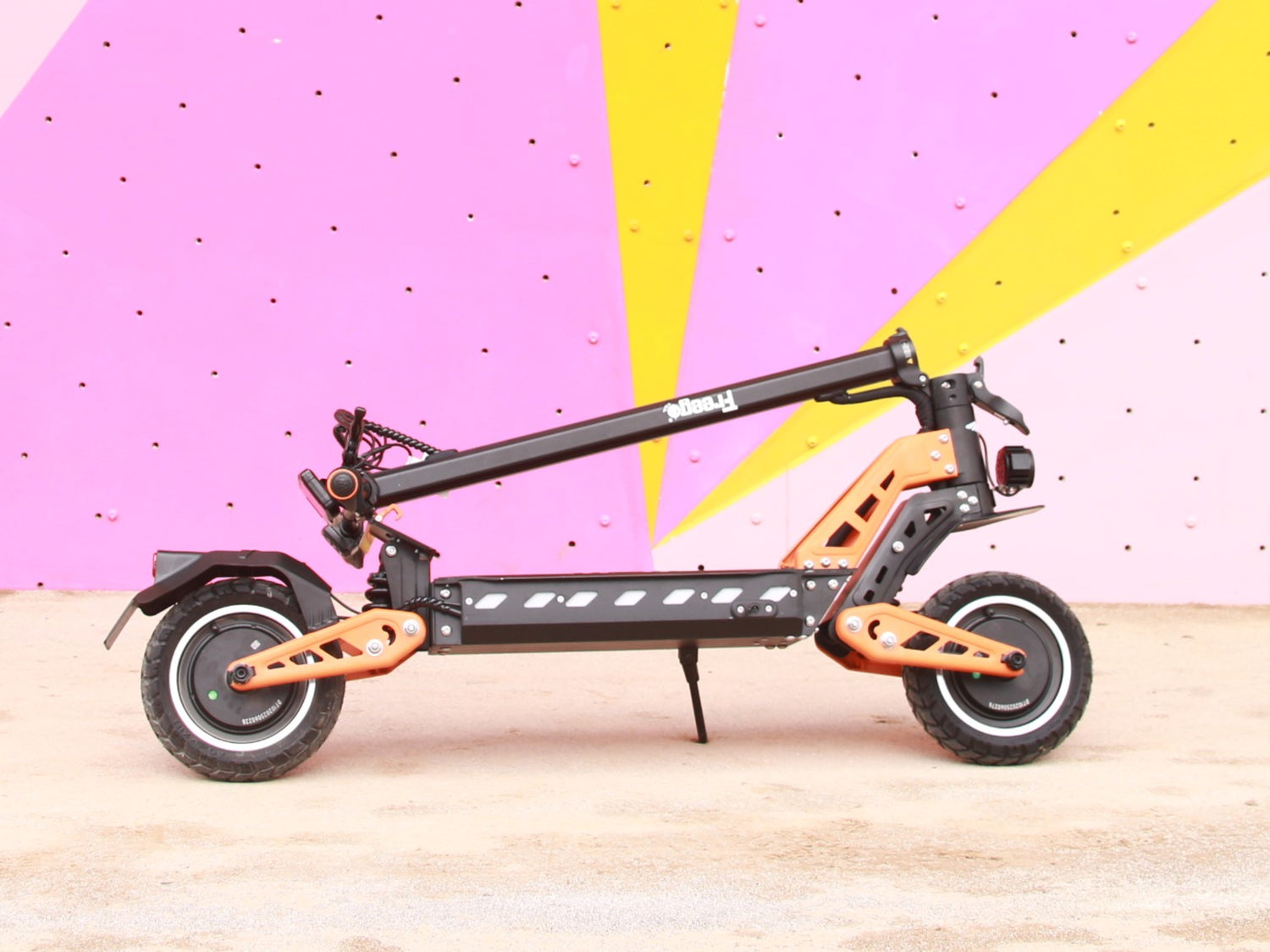 Orange and black electric scooter on a pink and yellow abstract background