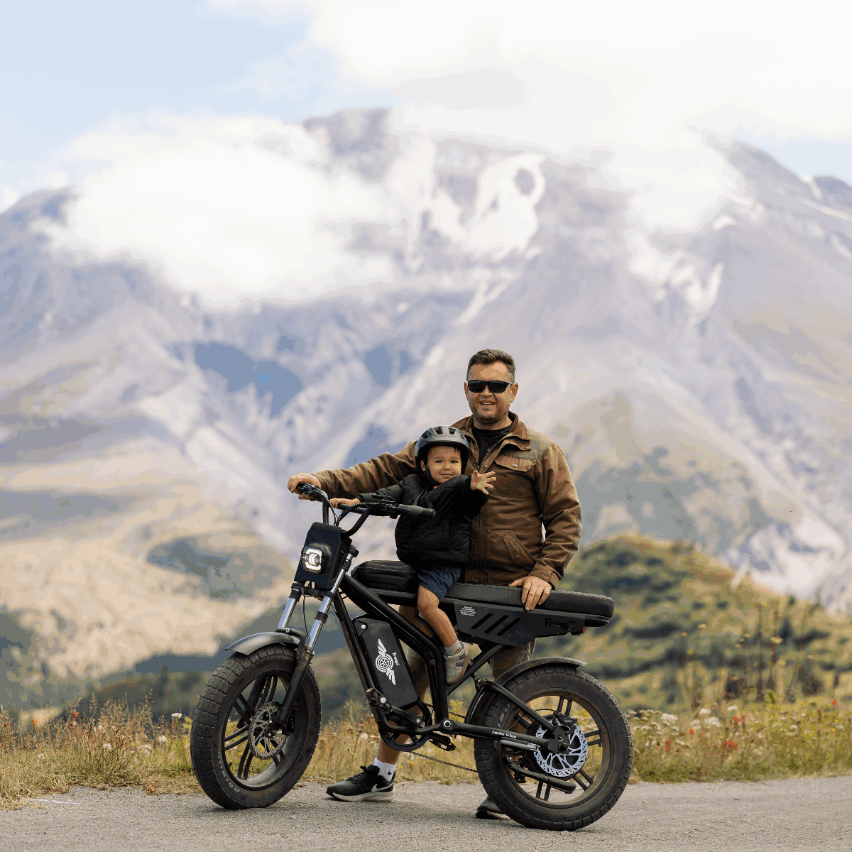 Man and child on a motorcycle with mountains in the background