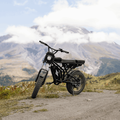Black electric bike on a dirt path with mountains in the background