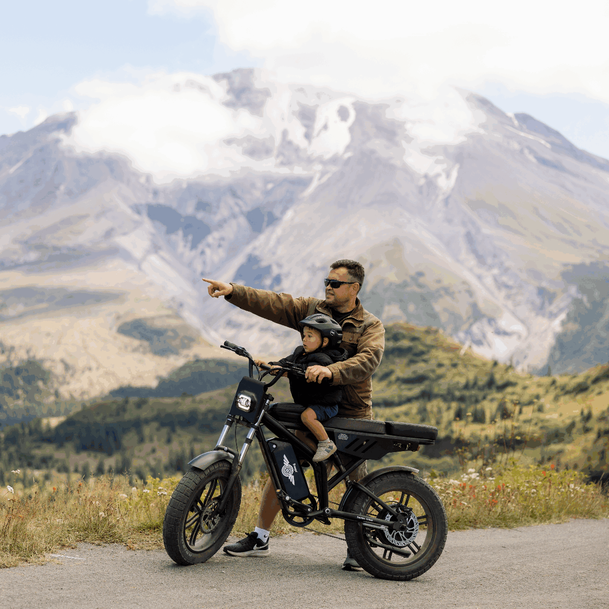 Man and child on a motorcycle with mountains in the background
