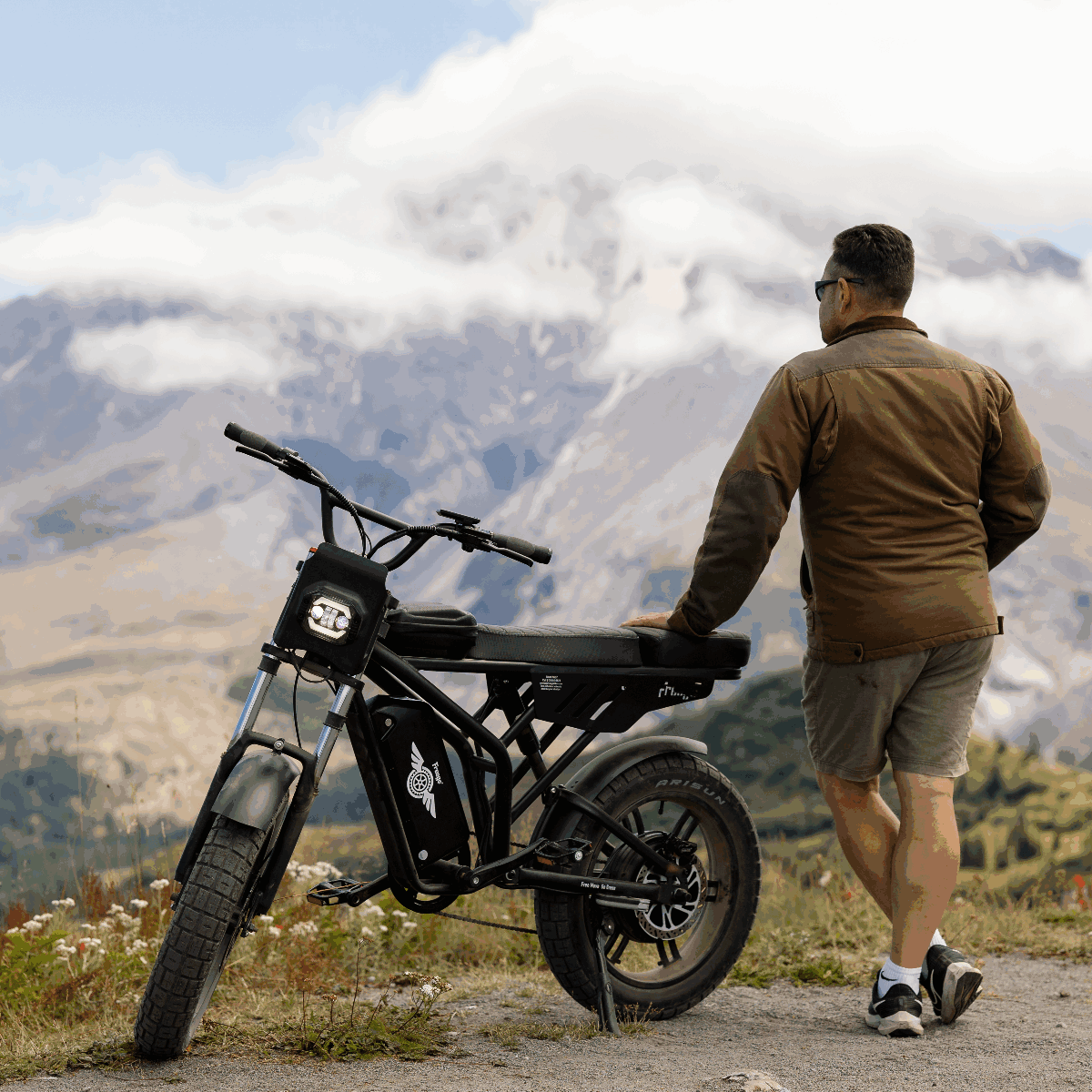 Man standing next to an electric bike with mountains in the background