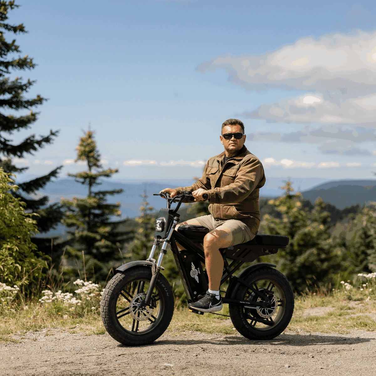Man riding an electric bike in a scenic outdoor setting with trees and mountains.