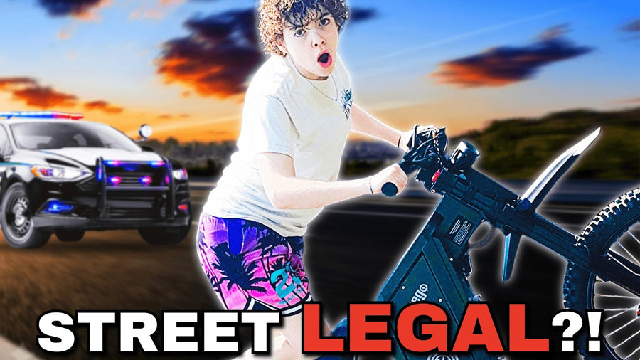 YouTube thumbnail featuring creator HDuke Rides riding Freego electric bike on highway with police car and sunset sky background