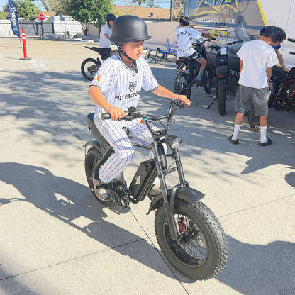 Helmeted rider testing a Freego M3 electric mini bike in a sunny parking lot.