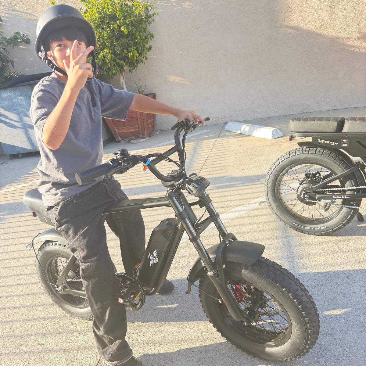 Helmeted rider making a peace sign while seated on a Freego M3 electric mini bike.