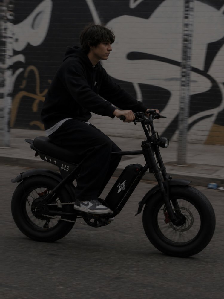 Young rider on a Freego M3 fat tire e-bike riding past a graffiti wall