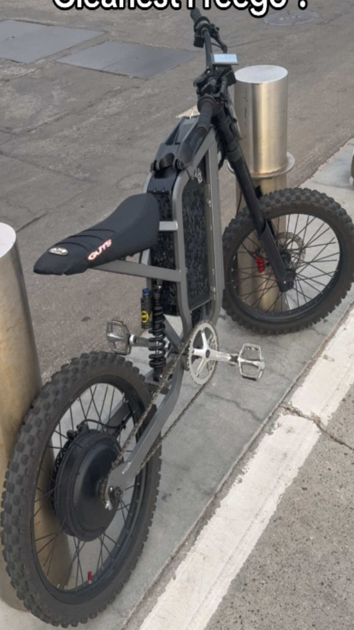 Black electric bike leaning against a metal post on a sidewalk