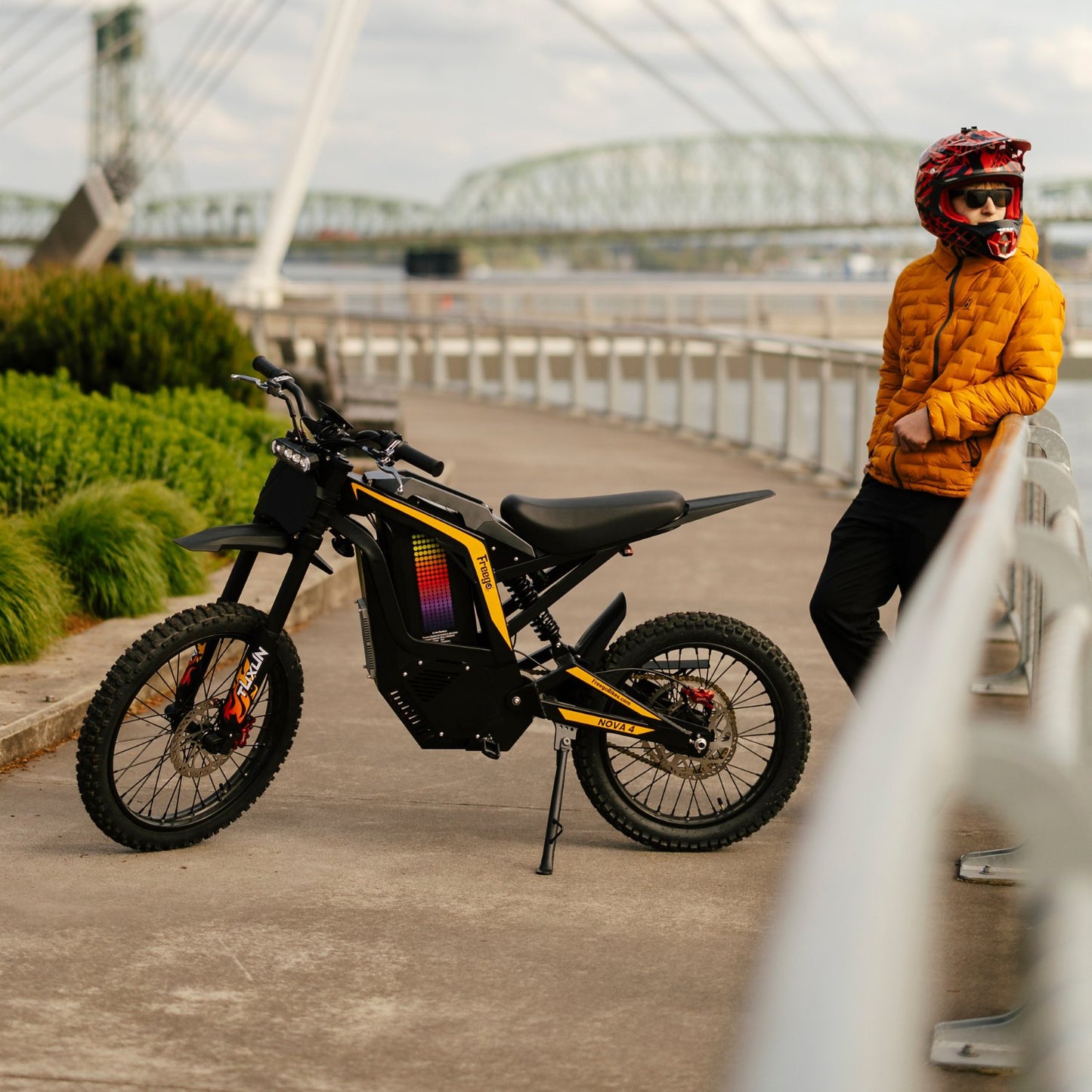 Freego Nova 4 electric dirt bike parked with rider near bridge walkway outdoors