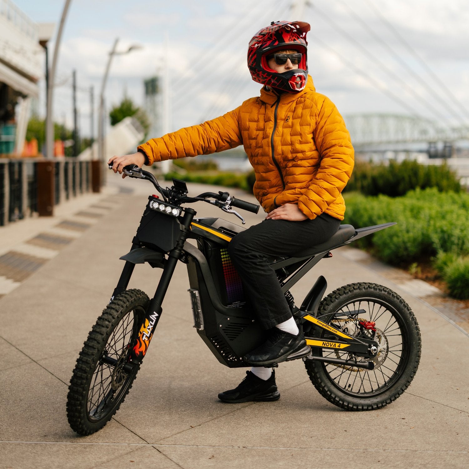Freego Nova 4 electric dirt bike with rider sitting on urban road near bridge