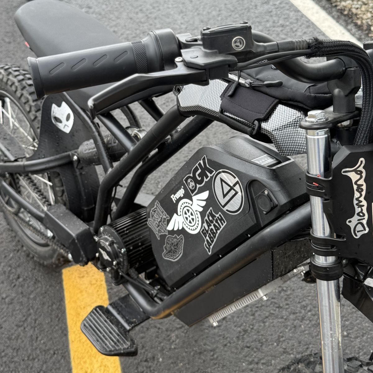 Close-up of a motorcycle handlebar with visible branding on a road.