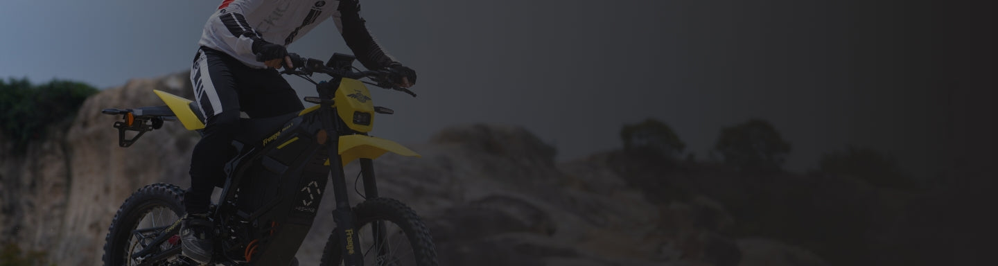 Person riding a motorcycle on a rocky trail with a dark background